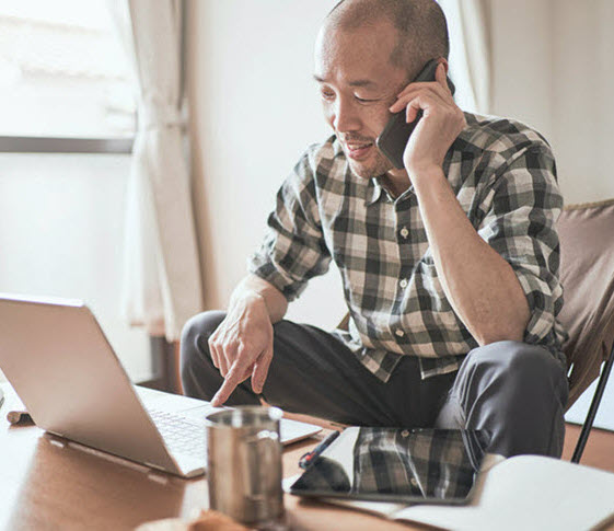 man on phone in front of laptop